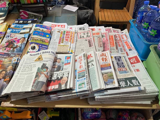 A table with many different Chinese language newspapers and magazines on it. The picture symbolises the goal of learning many Chinese characters in order to be able to read Chinese.